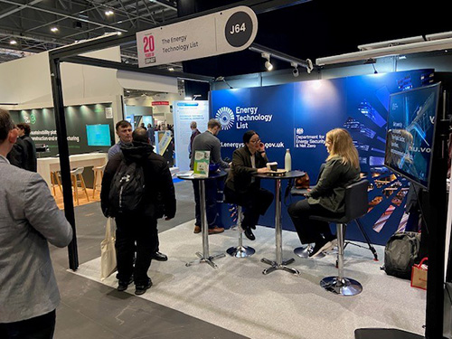 ETL stand at Futurebuild 2025 with team members engaging visitors, featuring Energy Technology List branding and display screen.